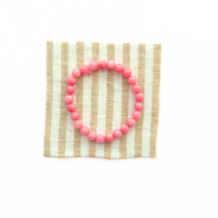 Pink beaded bracelet on a striped fabric background