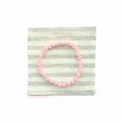Pink beaded bracelet on a striped fabric background