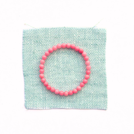 Pink beaded bracelet on a light green fabric background