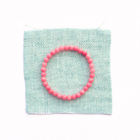 Thumbnail for Pink beaded bracelet on a light green fabric background