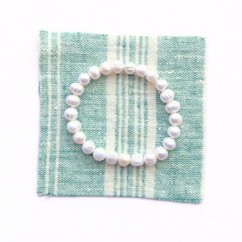 Pearl bracelet on a green and white striped fabric background