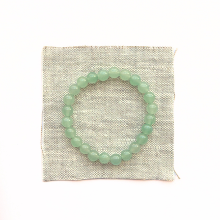 Green beaded bracelet on a textured white background